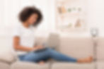 Women sits on sofa with laptop smiling